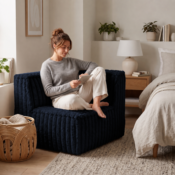 Personne assise sur un module d’angle droit de canapé modulable déhoussable bleu foncé, assise épaisse en fourrure côtelée