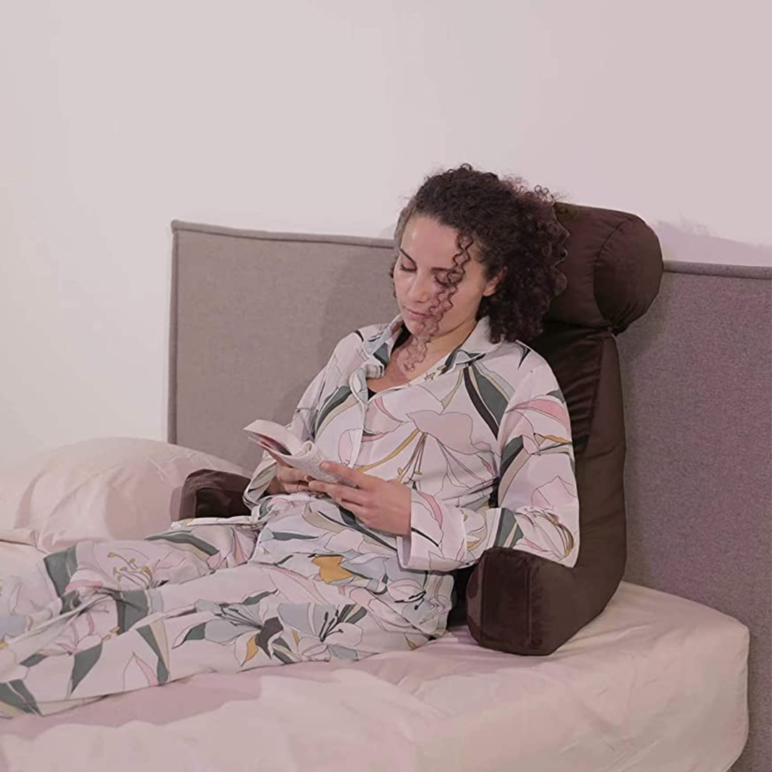 Personne calée sur un coussin de lecture en velours sur un lit