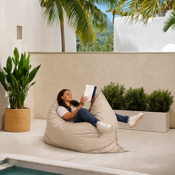 Personne allongée sur un pouf extérieur 140x180 cm au bord d’une piscine, utilisé comme assise confortable.