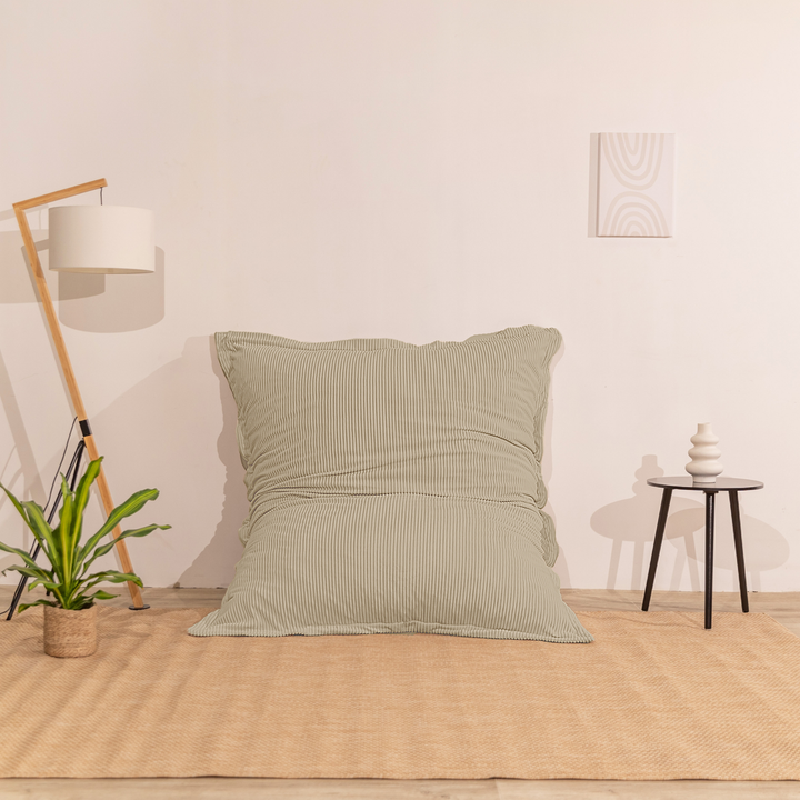 Pouf 140x180 beige en velours côtelé déhoussable, appuyé contre un mur dans un décor d&