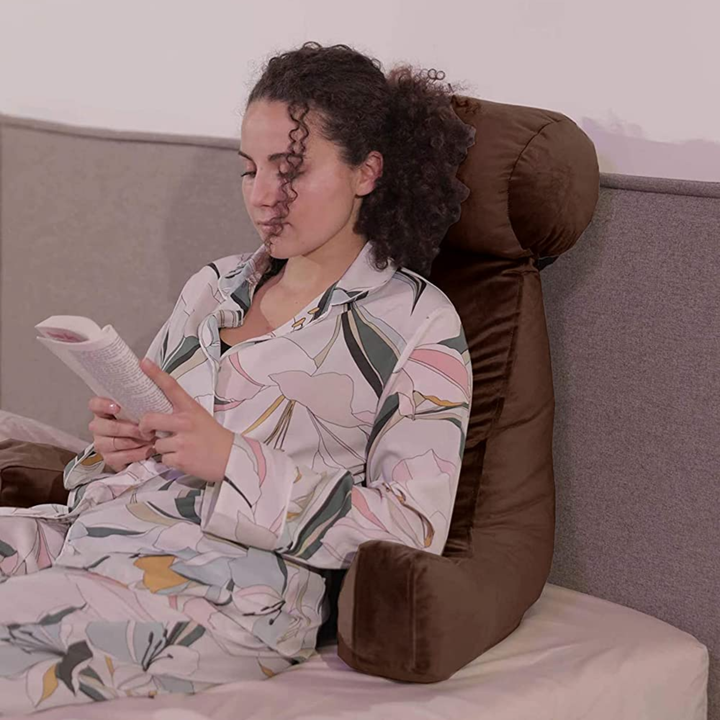 Personne calée sur un coussin de lecture en velours sur un lit
