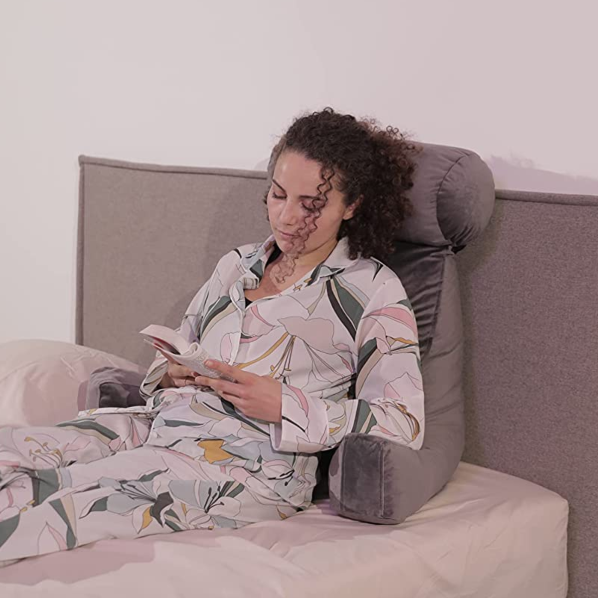 Personne calée sur un coussin de lecture en velours sur un lit
