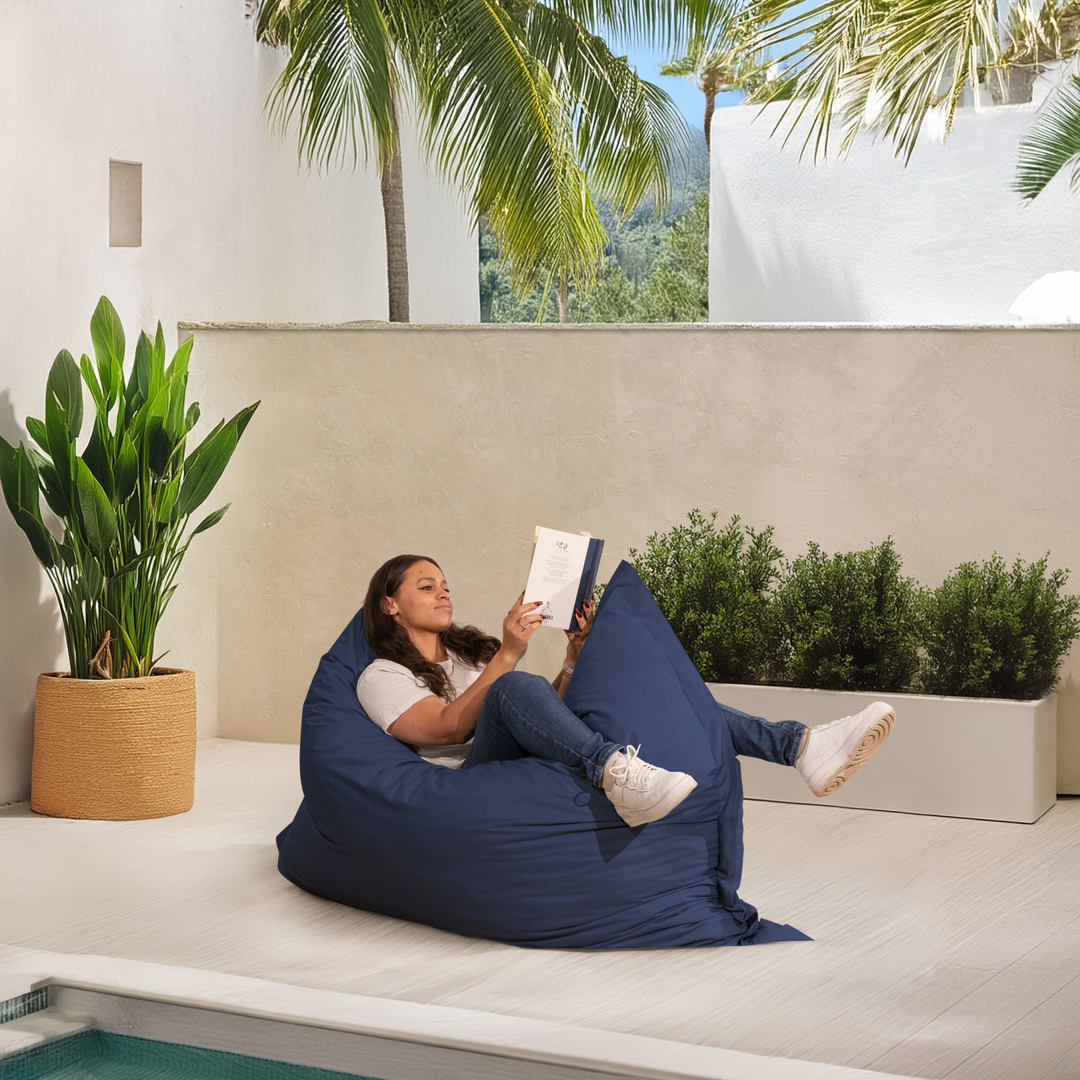 Personne allongée sur un pouf extérieur 140x180 cm au bord d’une piscine, utilisé comme assise confortable.
