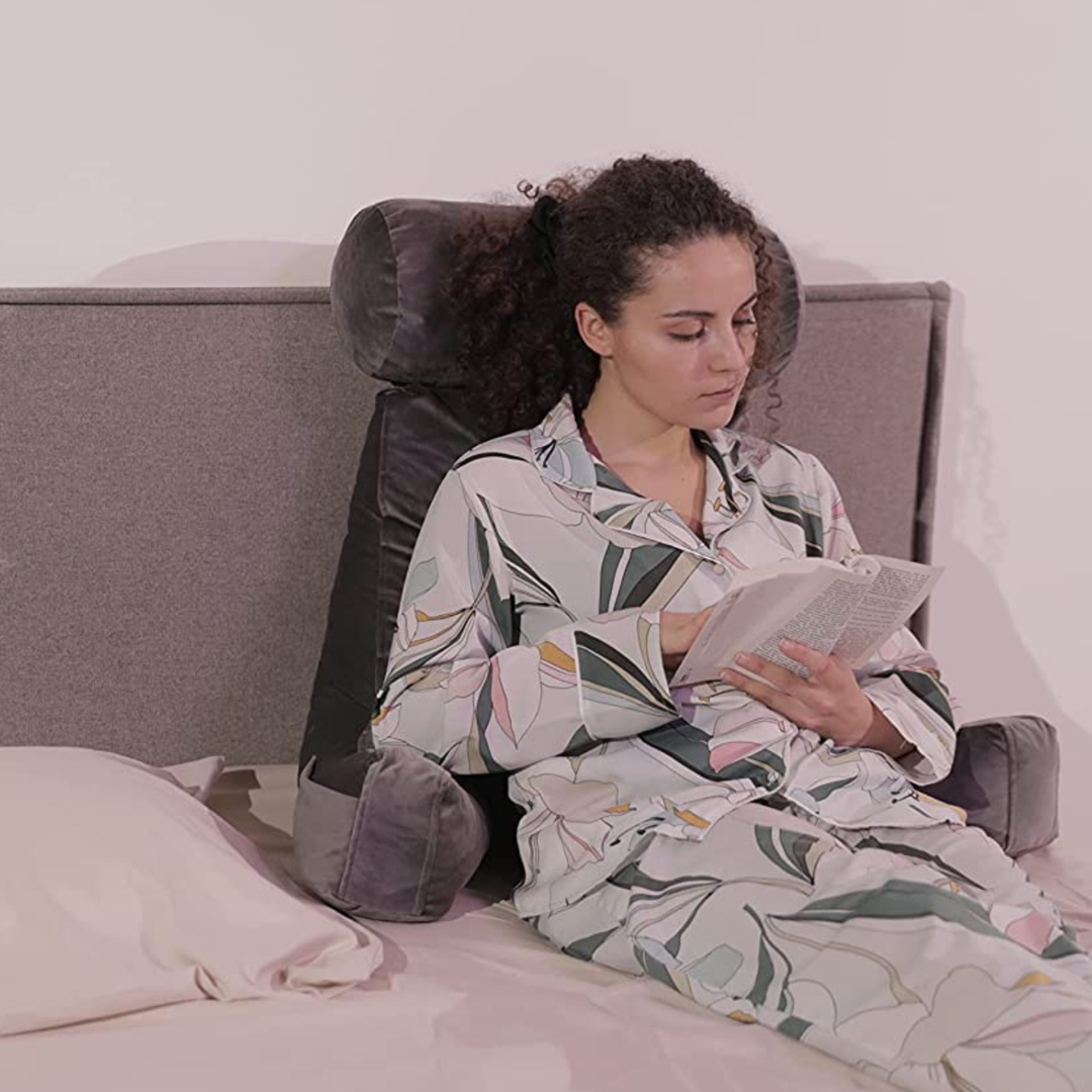Personne calée sur un coussin de lecture en velours sur un lit