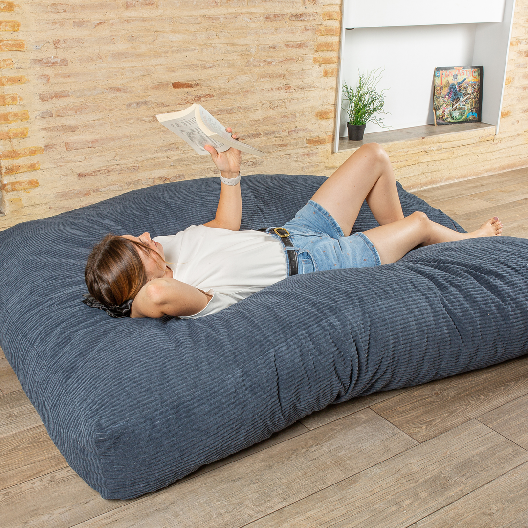 Personne allongée sur le pouf-lit convertible 2en1, utilisé en couchage pour se détendre