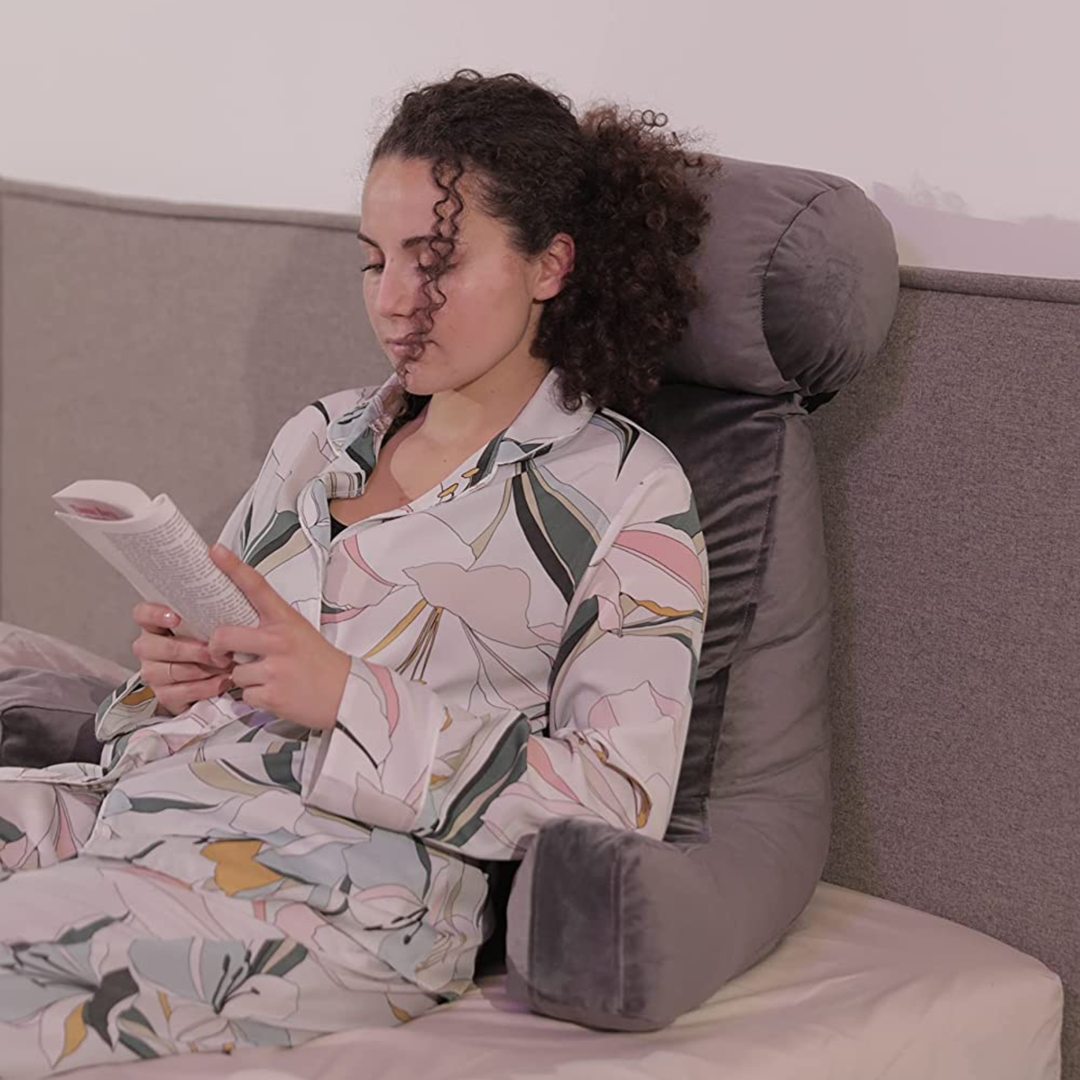 Personne calée sur un coussin de lecture en velours sur un lit