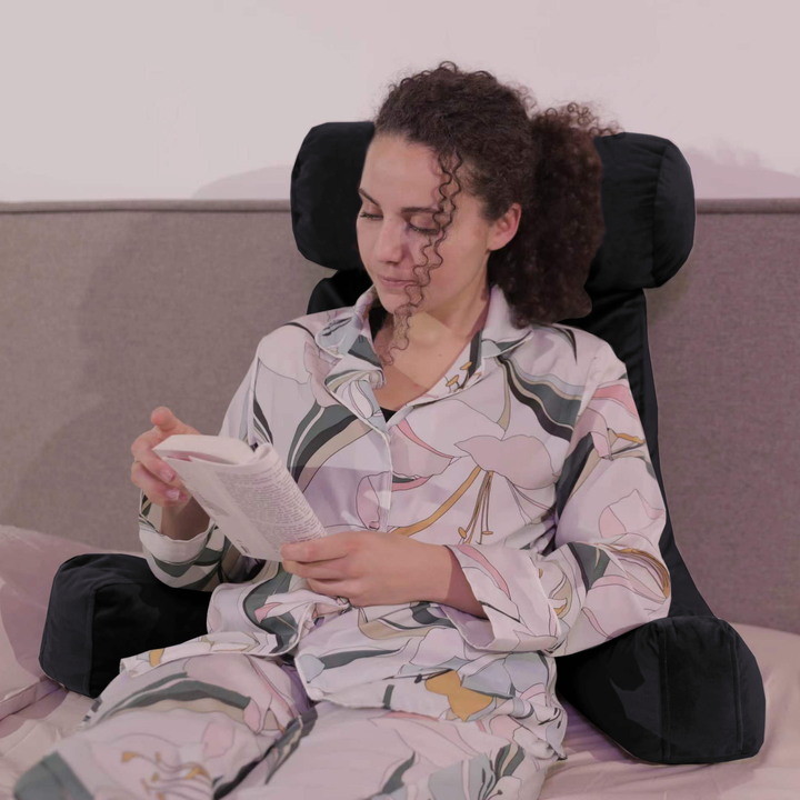 Personne calée sur un coussin de lecture en velours sur un lit