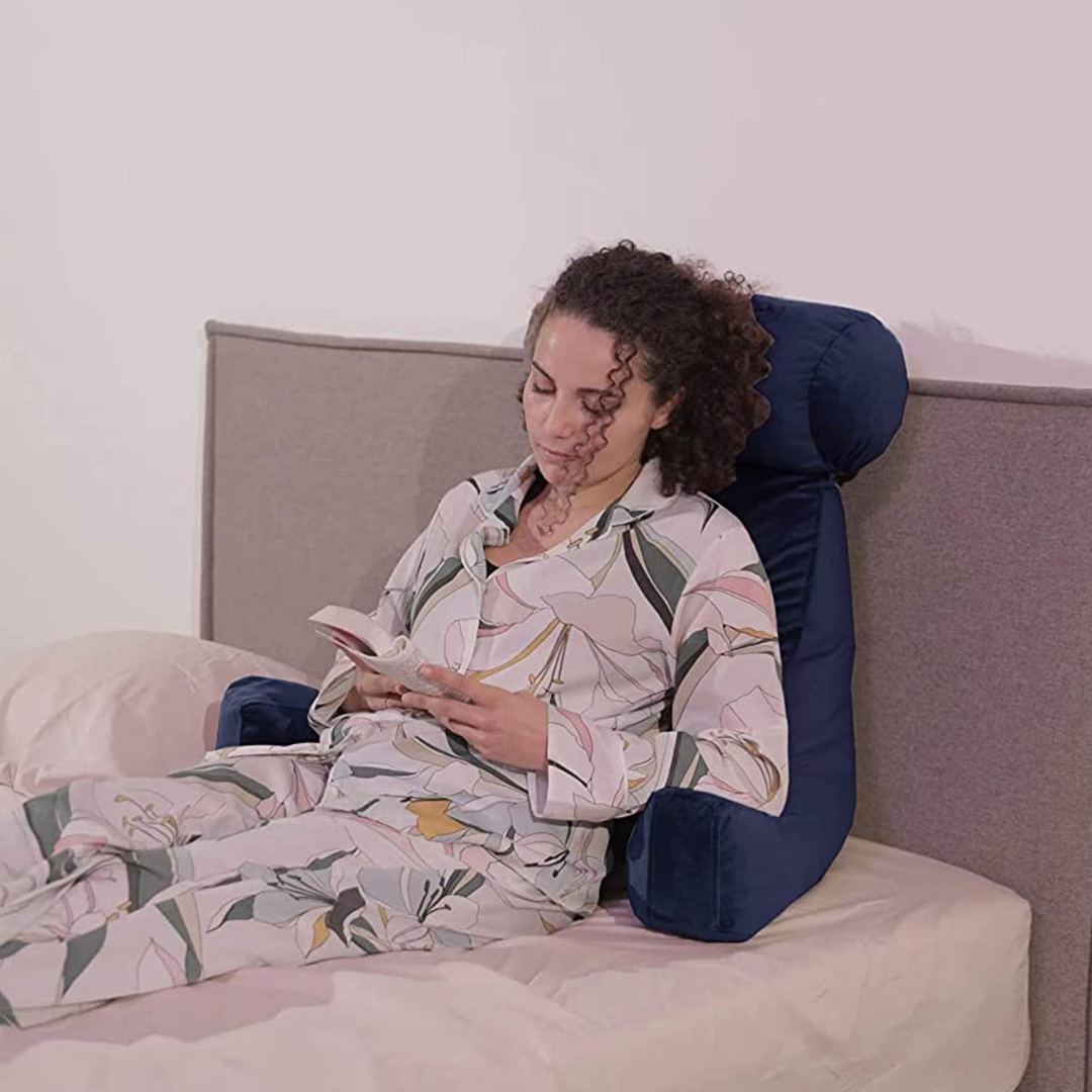 Personne calée sur un coussin de lecture en velours sur un lit