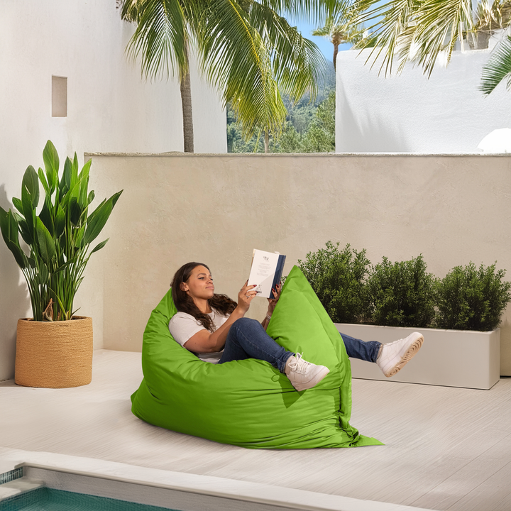 Personne allongée sur un pouf extérieur 140x180 cm au bord d’une piscine, utilisé comme assise confortable.