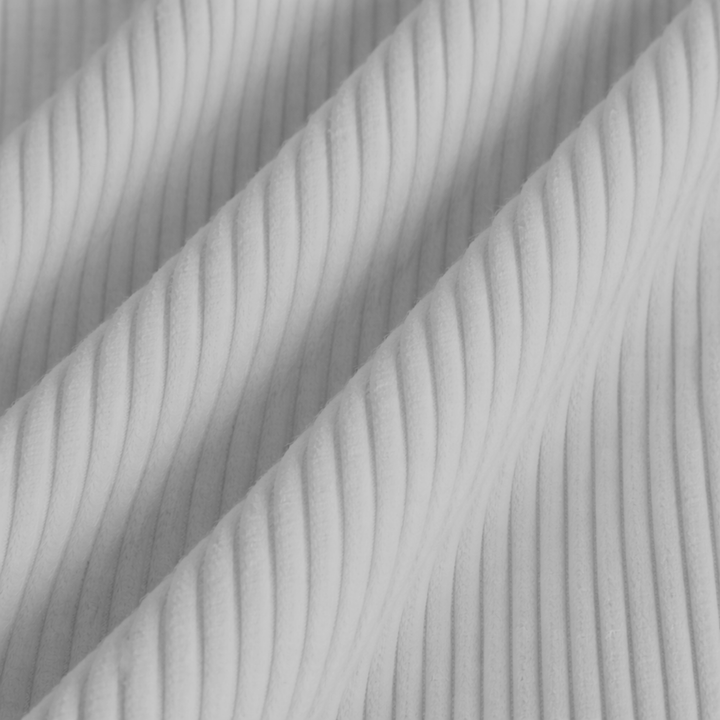 Détail du tissu du pouf en velours côtelé gris clair, relief strié.