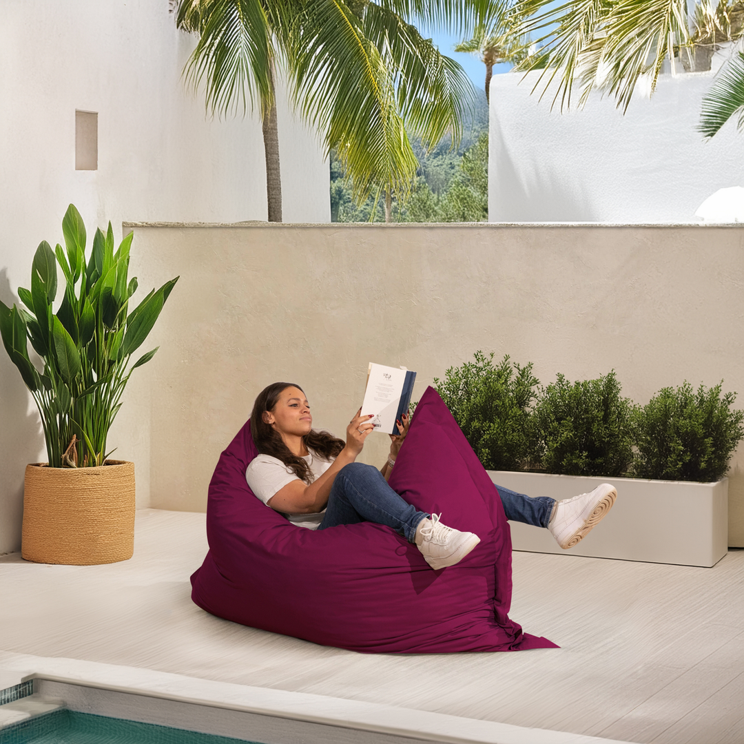 Personne allongée sur un pouf extérieur 140x180 cm au bord d’une piscine, utilisé comme assise confortable.
