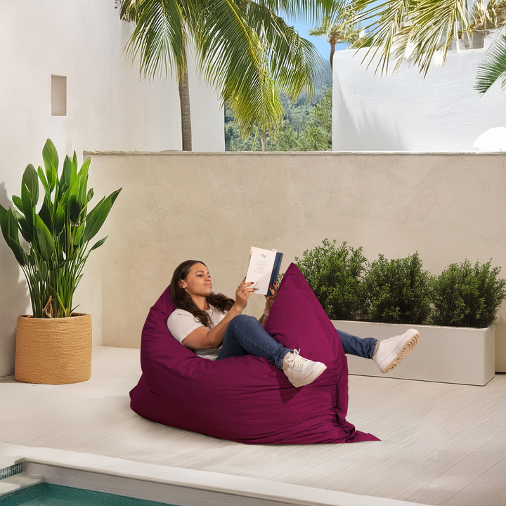 Personne allongée sur un pouf extérieur 140x180 cm au bord d’une piscine, utilisé comme assise confortable.