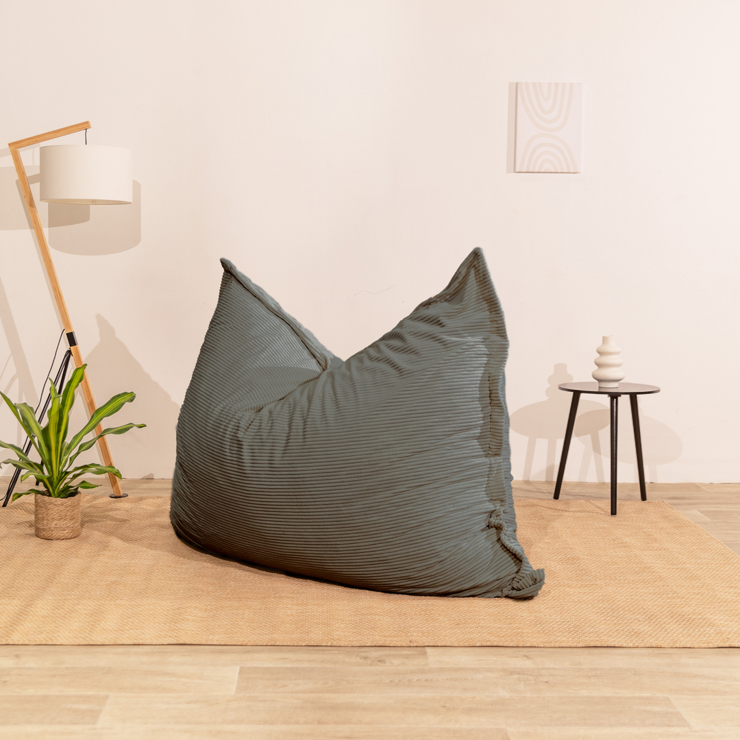 Pouf 140x180 cm en velours côtelé gris foncé, posé au sol dans un décor d&