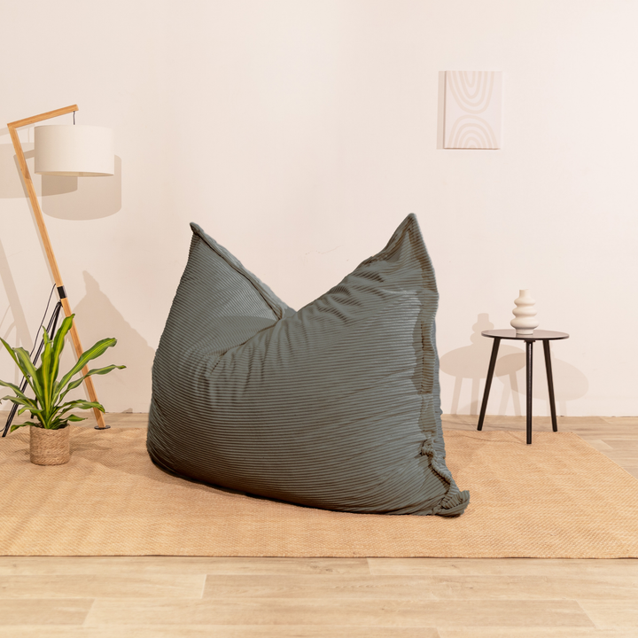 Pouf 140x180 cm en velours côtelé gris foncé, posé au sol dans un décor d&