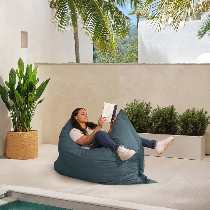 Personne allongée sur un pouf extérieur 140x180 cm au bord d’une piscine, utilisé comme assise confortable.