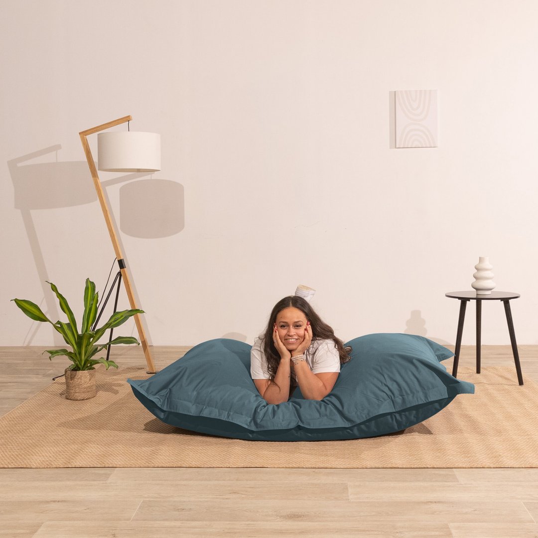 Personne allongée sur un pouf extérieur 140x180 cm dans un intérieur, démontrant son confort.