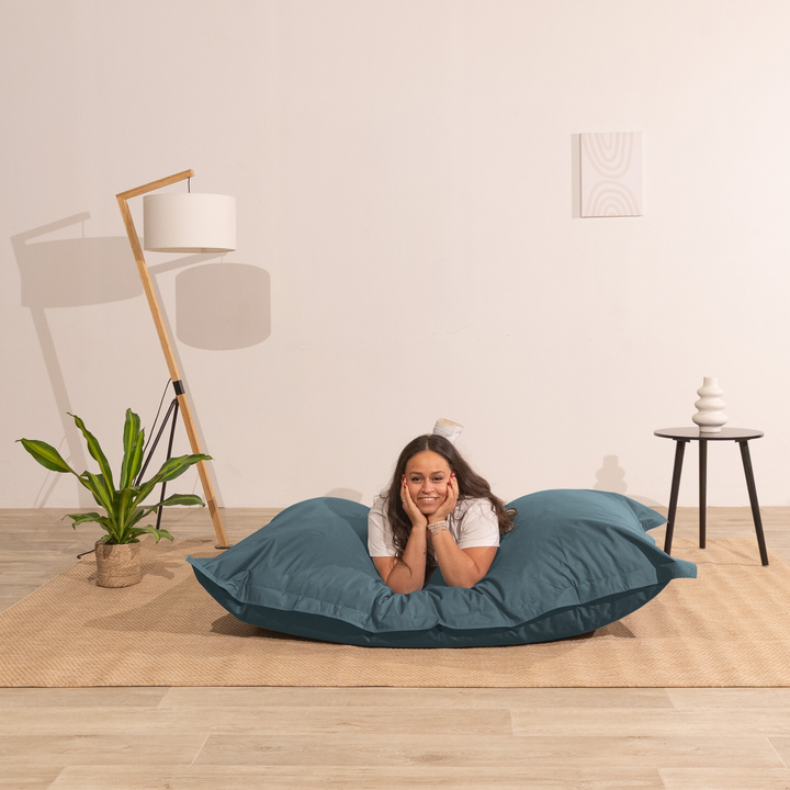 Personne allongée sur un pouf extérieur 140x180 cm dans un intérieur, démontrant son confort.