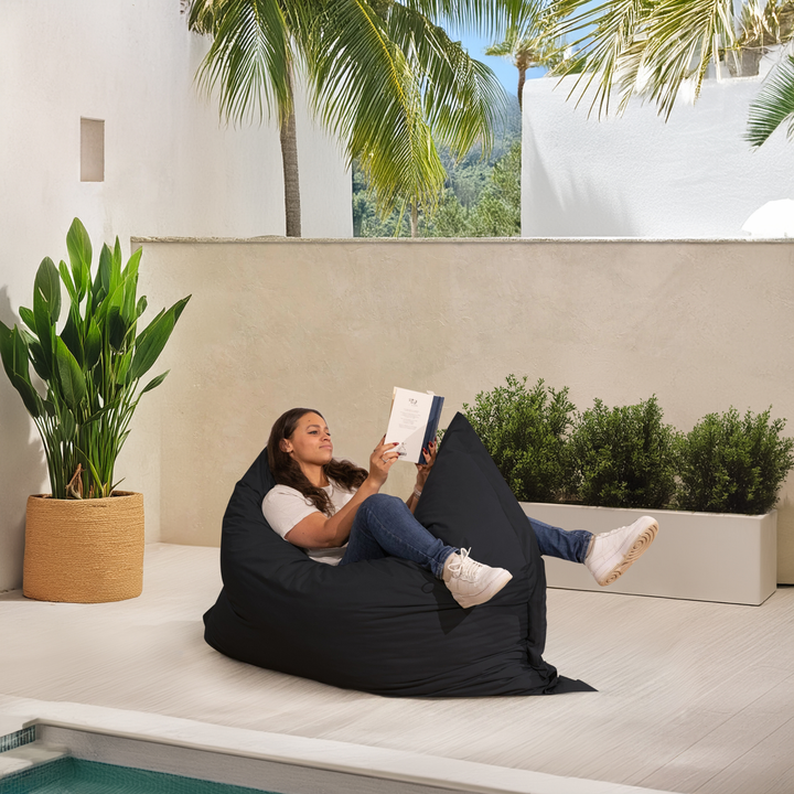 Personne allongée sur un pouf extérieur 140x180 cm au bord d’une piscine, utilisé comme assise confortable.