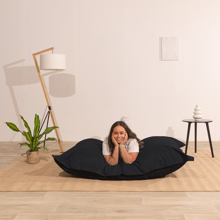 Personne allongée sur un pouf extérieur 140x180 cm dans un intérieur, démontrant son confort.
