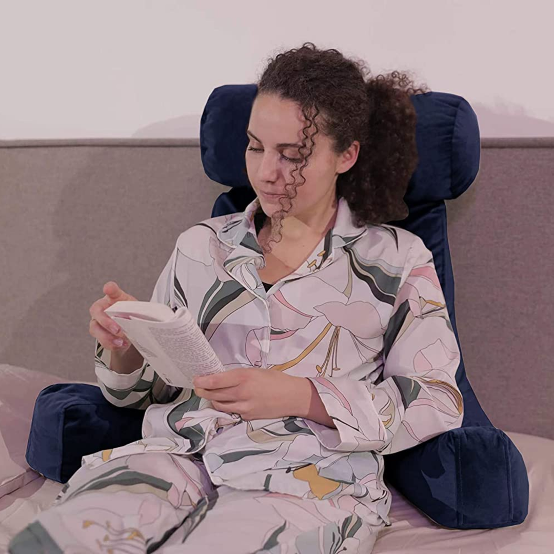 Personne calée sur un coussin de lecture en velours sur un lit