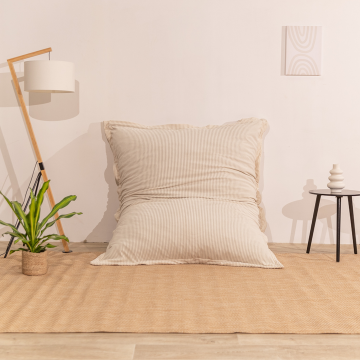 Pouf 140x180 blanc cassé en velours côtelé déhoussable, appuyé contre un mur dans un décor d&