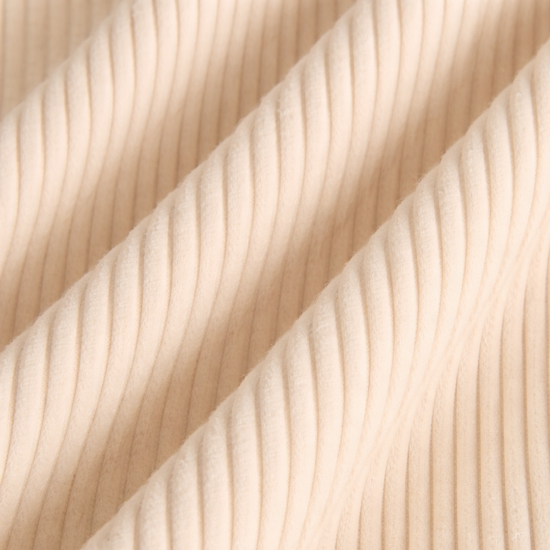 Détail du velours côtelé du pouf déhoussable, blanc cassé, reliefs verticaux serrés.