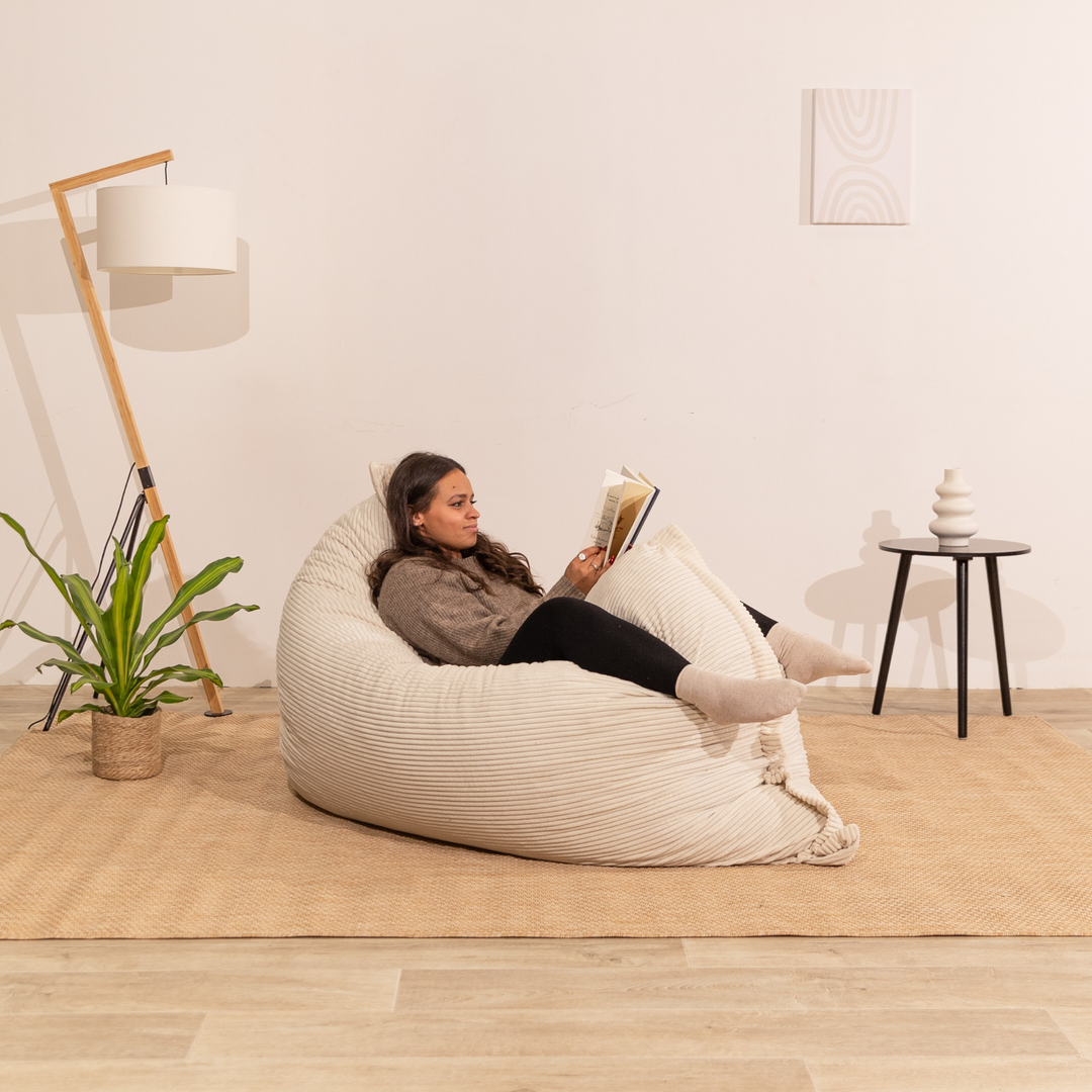 Personne assise sur un pouf 140x180 cm blanc cassé en velours côtelé, dans un décor d&